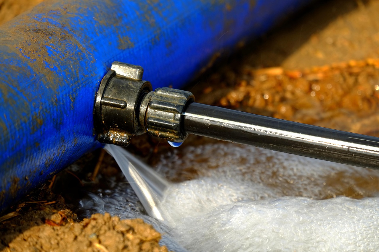 Water spraying from a leak at a fitting on a damaged underground pipe
