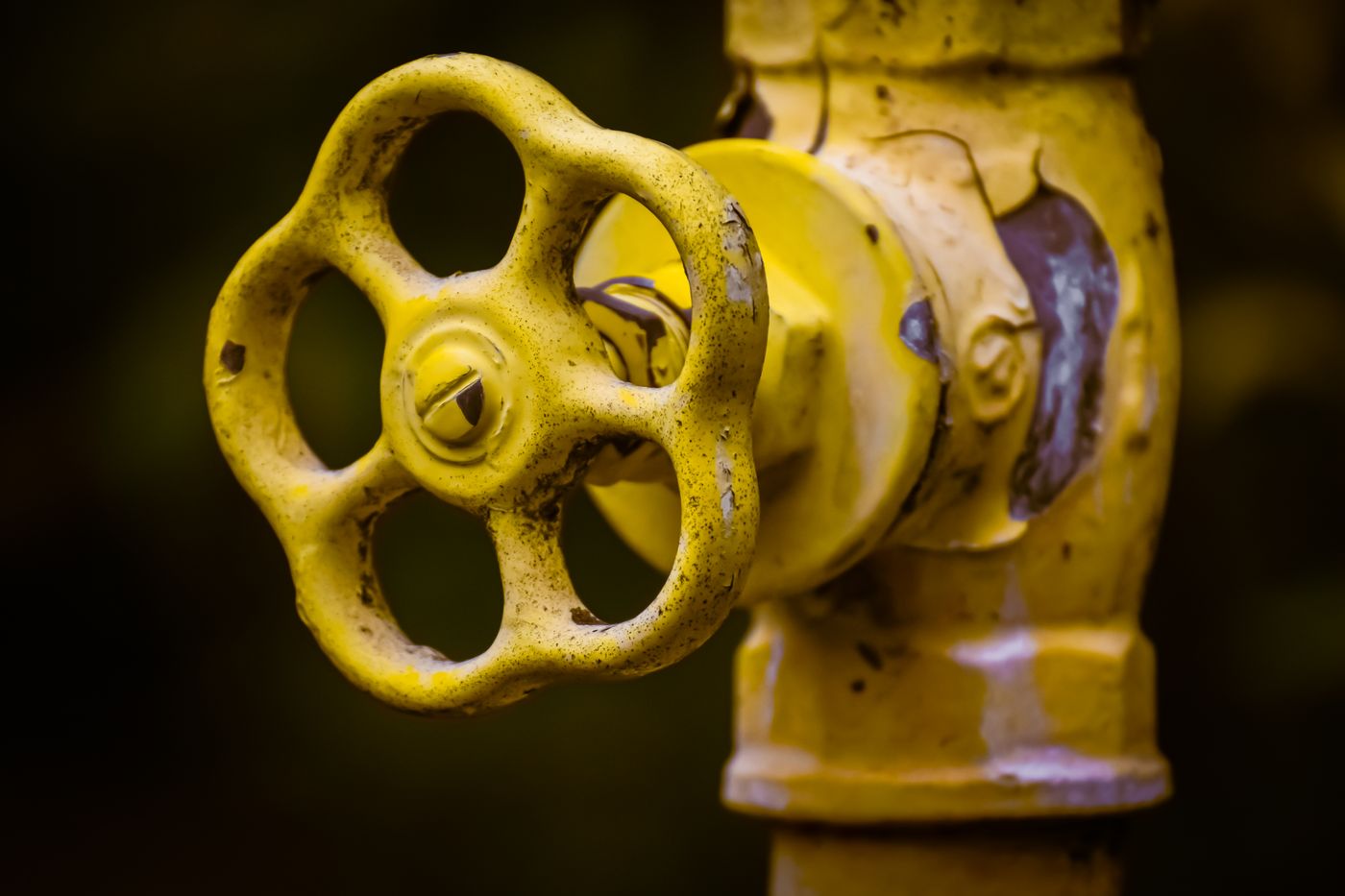 Close-up of a yellow shut-off valve handwheel on a yellow gas pipe