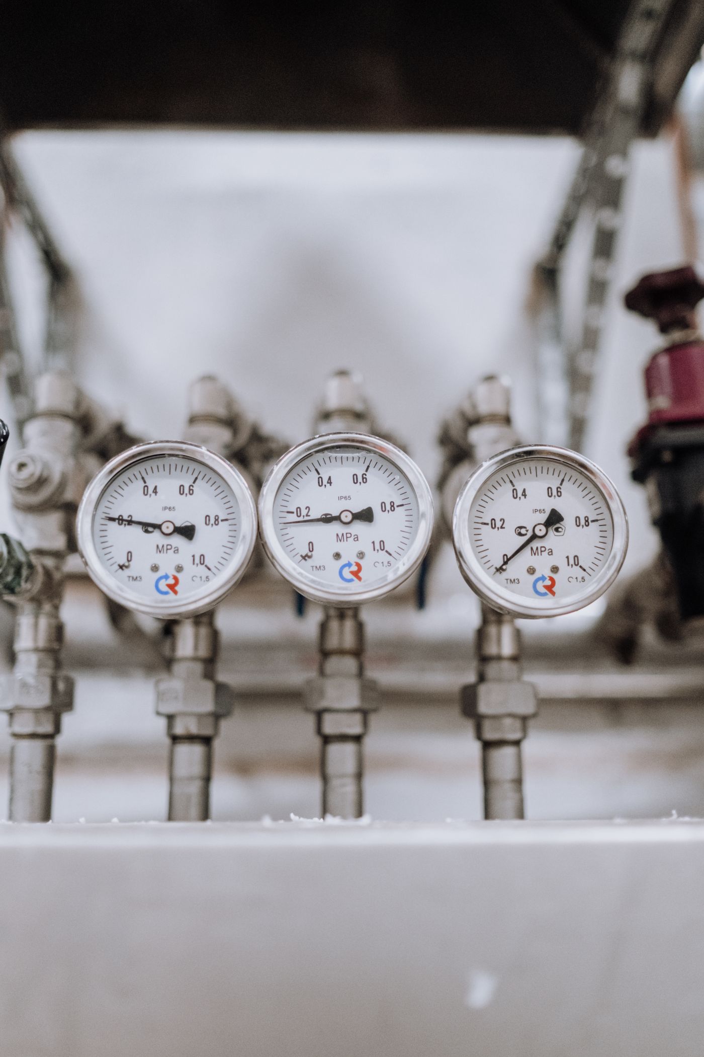 Three analog pressure gauges mounted on metal piping
