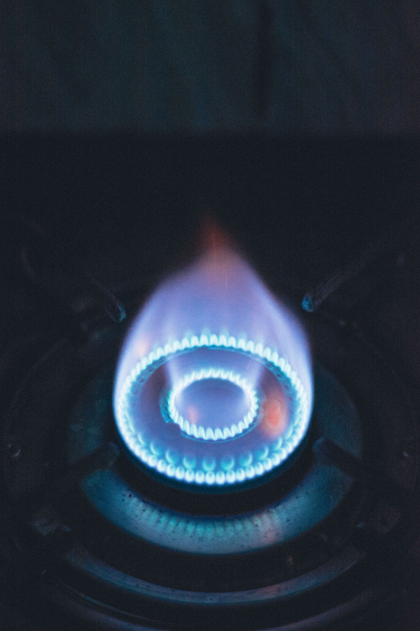 Close-up of a lit blue flame ring on a gas stove burner