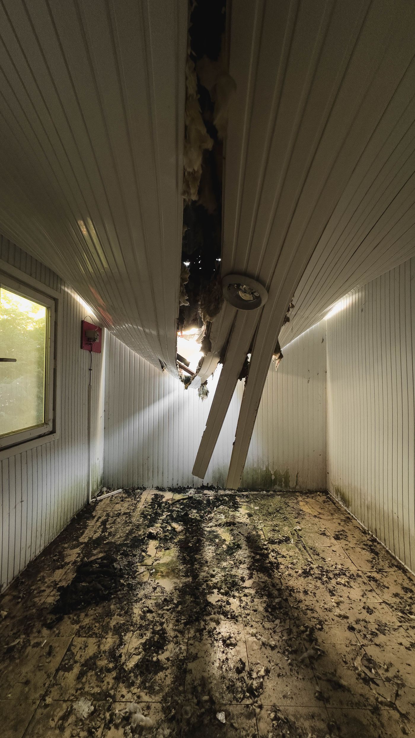 A water-damaged interior with a stained, broken ceiling and soiled floor showing the hidden damage a leak can cause