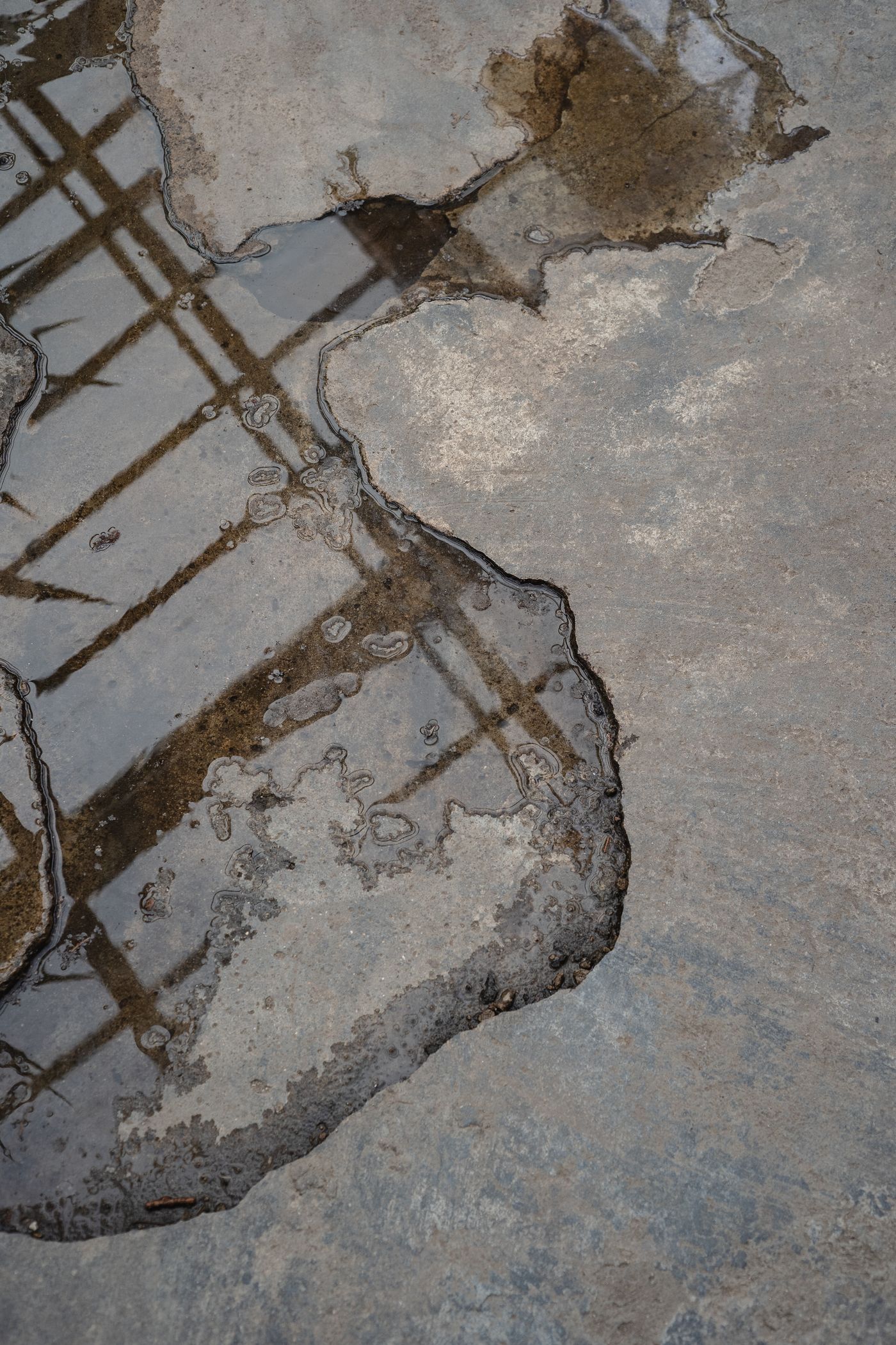 Water pooling and spreading across a bare concrete floor surface