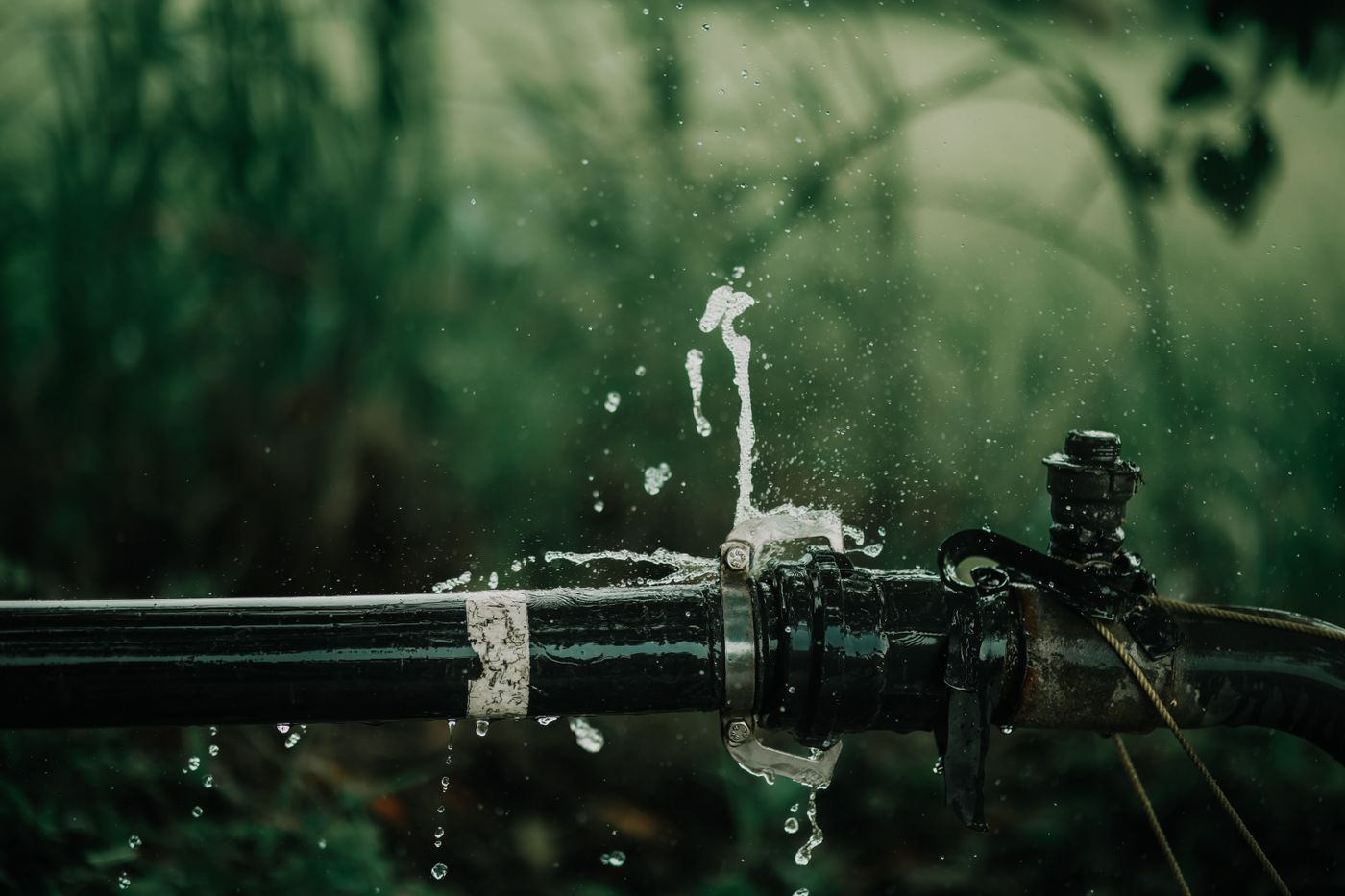 Water spraying from a failed joint on a metal pipe where the fitting has given way