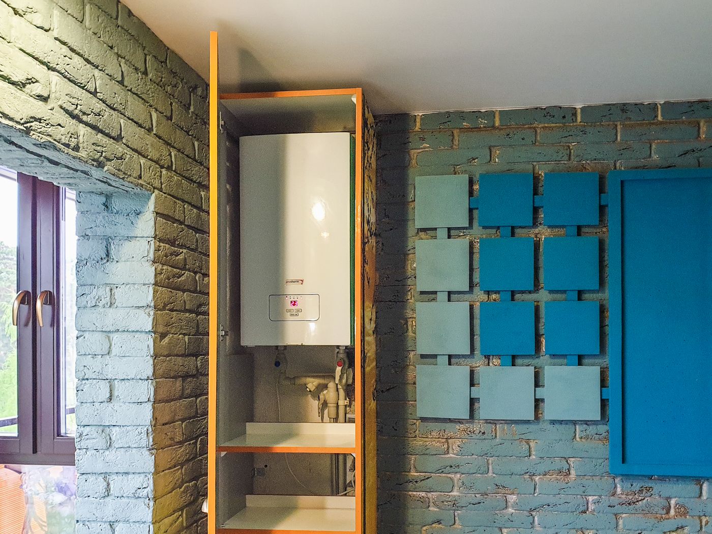 A wall-mounted residential water heater unit in an alcove with visible pipe connections below